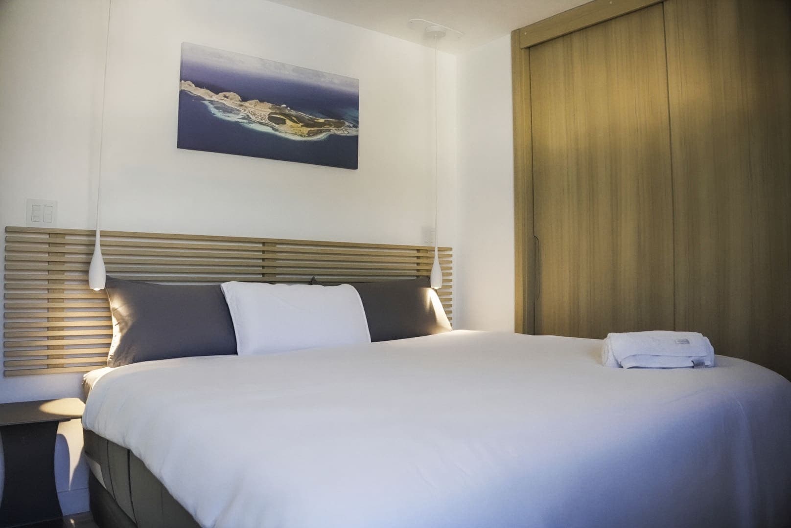 Habitación principal con cama grande, cabecero de listones y armario de madera