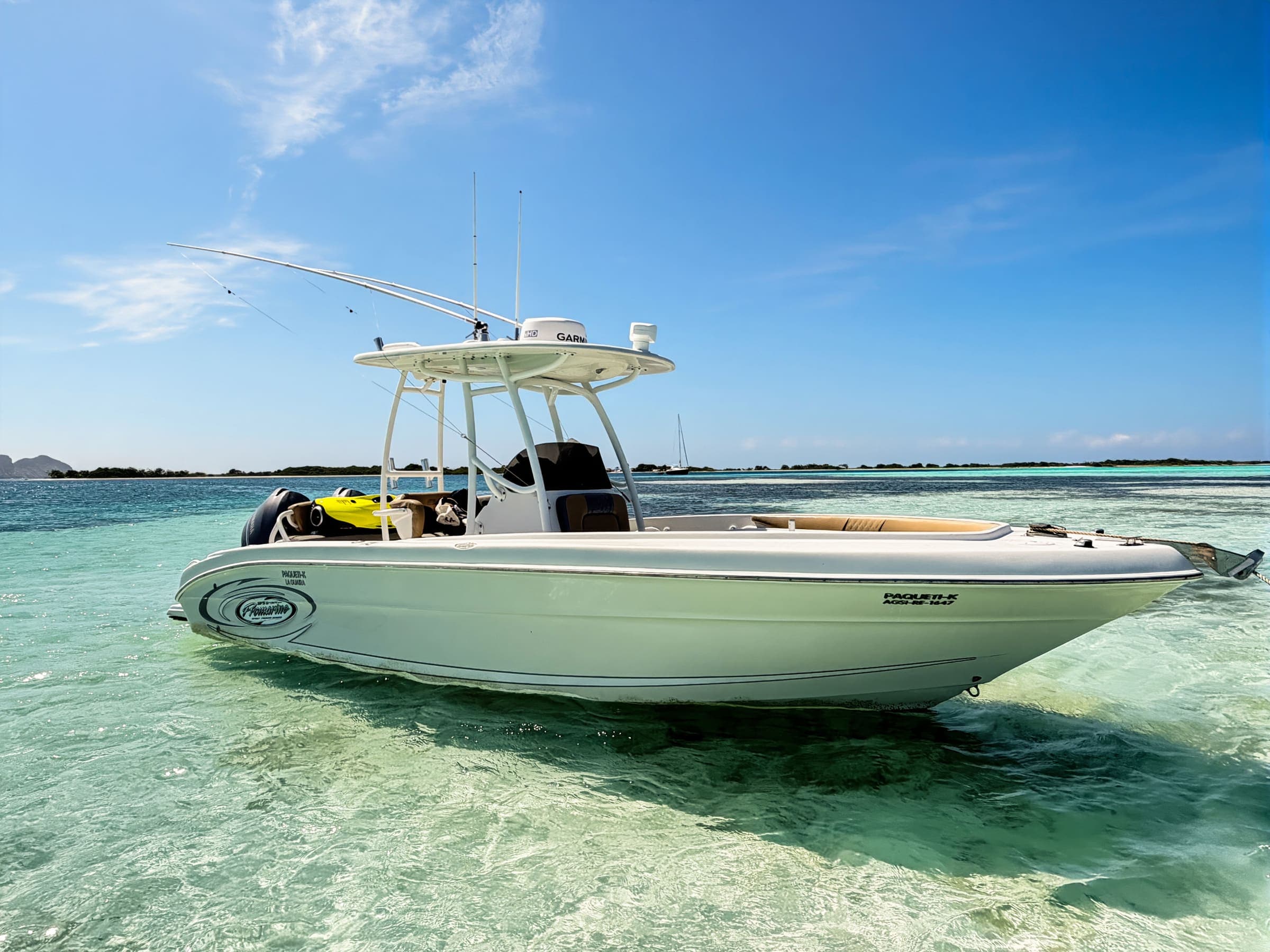 La lancha fondeada frente a un cayo, con un velero al fondo
